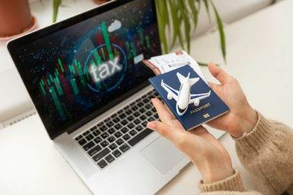 woman holding toy plane, tickets, laptop and taxes